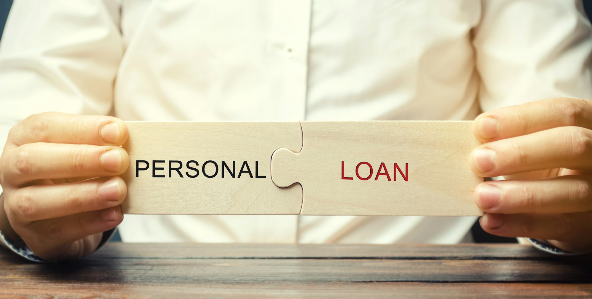 A man collects wooden puzzles with the word Personal Loan